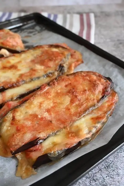 Dettaglio di una fetta di melanzana al forno con pomodoro e mozzarella filante e basilico