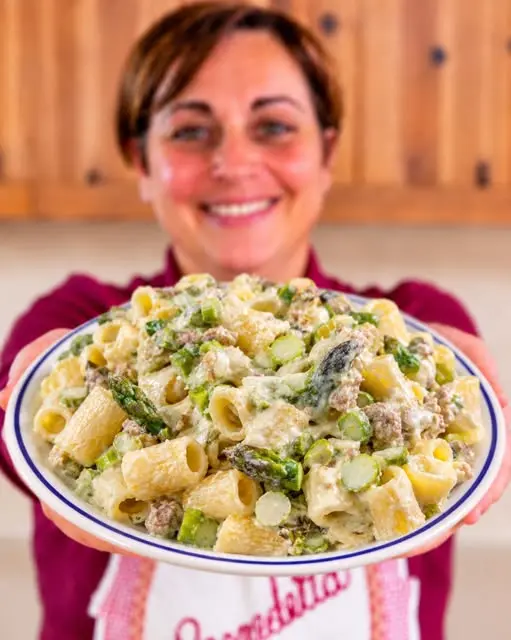 Dettaglio ravvicinato di una forchettata di pasta con crema di asparagi e salsiccia sgranata