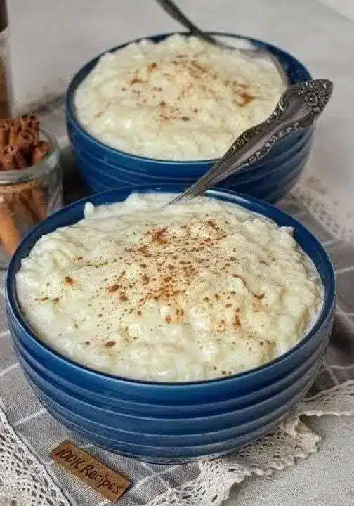 Budino di riso servito in una ciotolina di ceramica con una spolverata di cannella e una fogliolina di menta