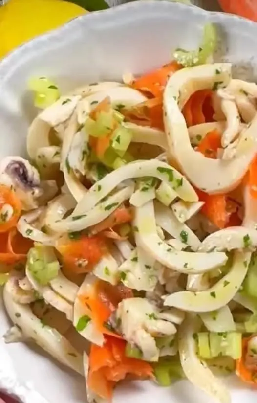 Insalata di seppie servita in un piatto elegante con guarnizione di limone
