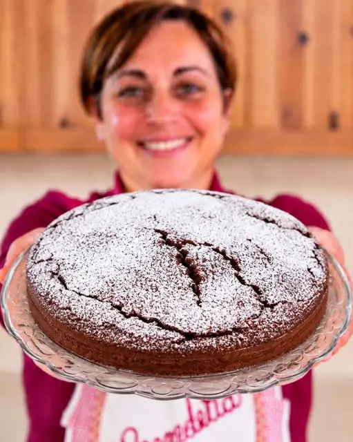 Fetta di torta al cioccolato soffice servita su un piatto bianco con panna montata