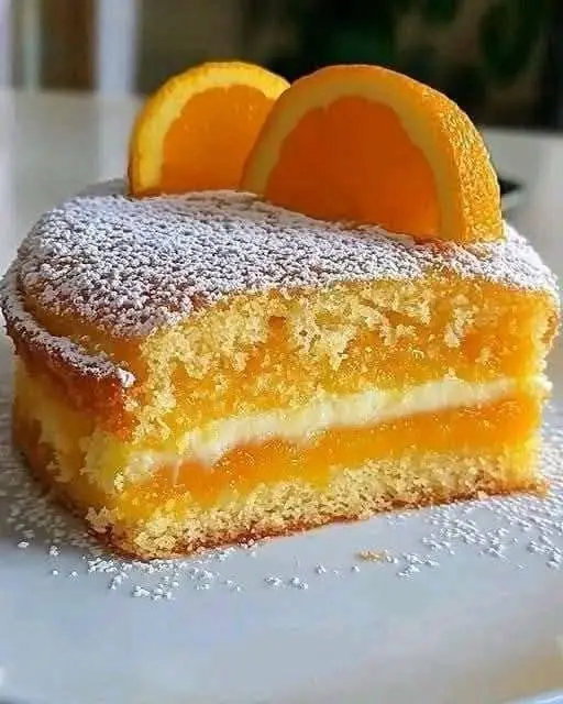 Fetta di torta all'arancia servita con un ciuffo di crema